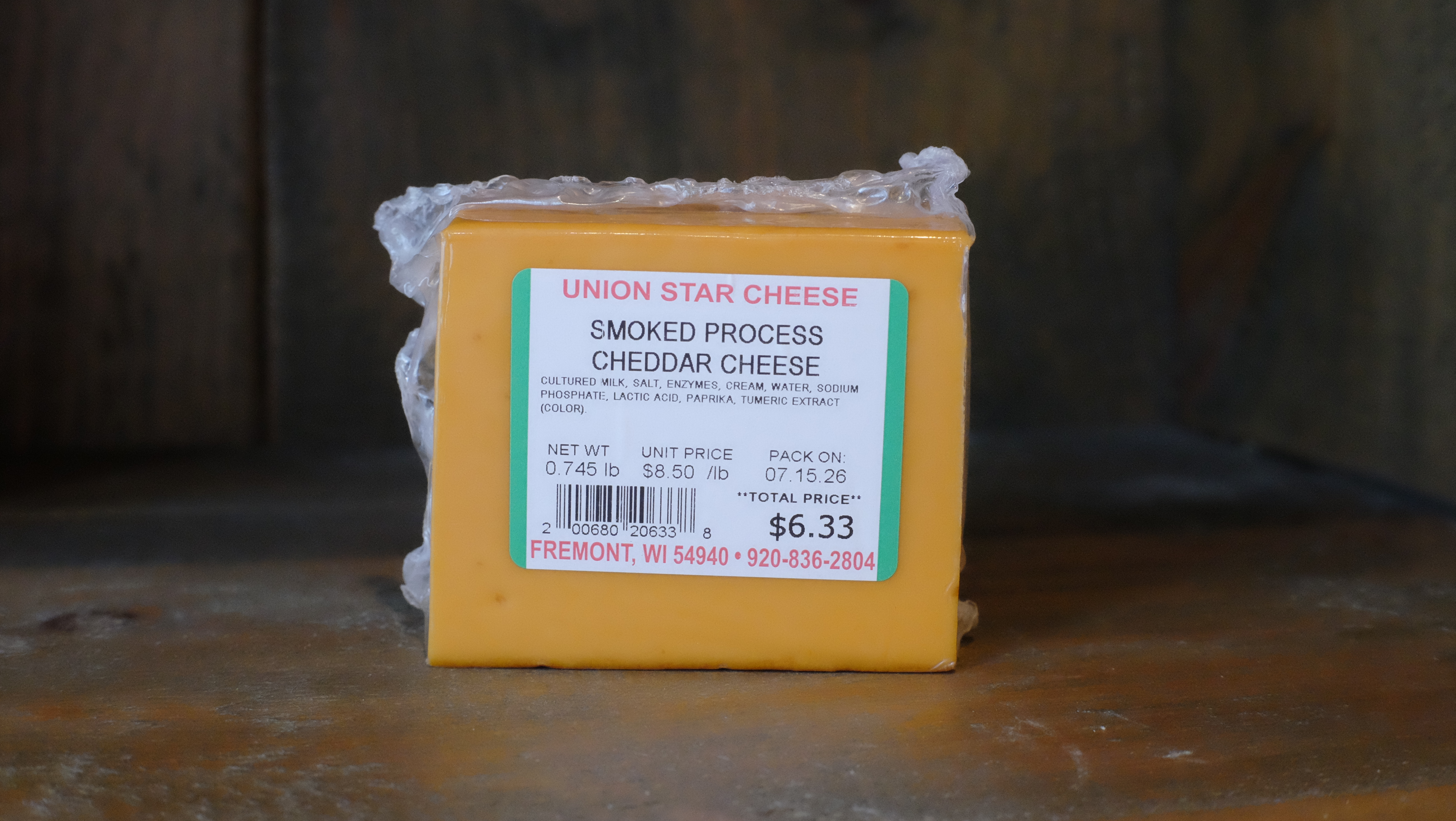 Block of cold-smoked cheddar cheese on a wooden cutting board
